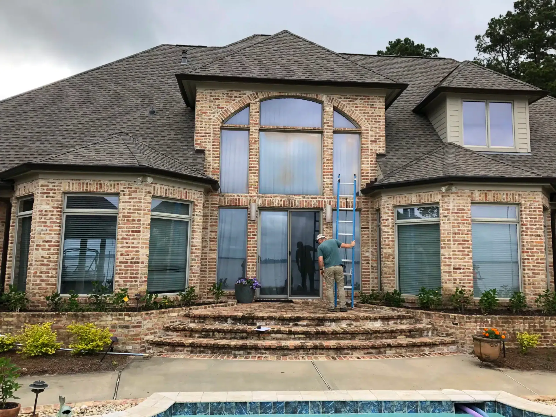 Two-story brick home with a tall arched window over the pool, a Heritage Windows & Doors project in Jackson, Mississippi