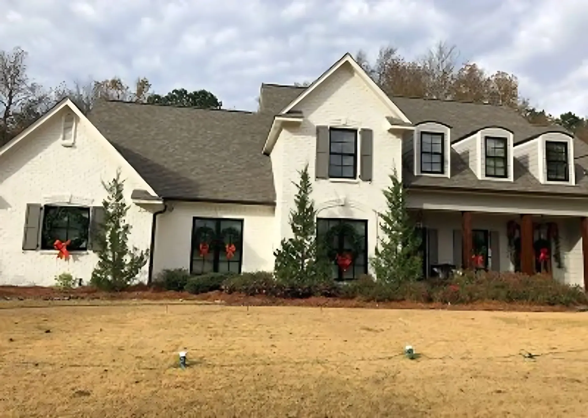 White brick two-story home in Jackson, Mississippi with new black-framed windows and holiday wreaths