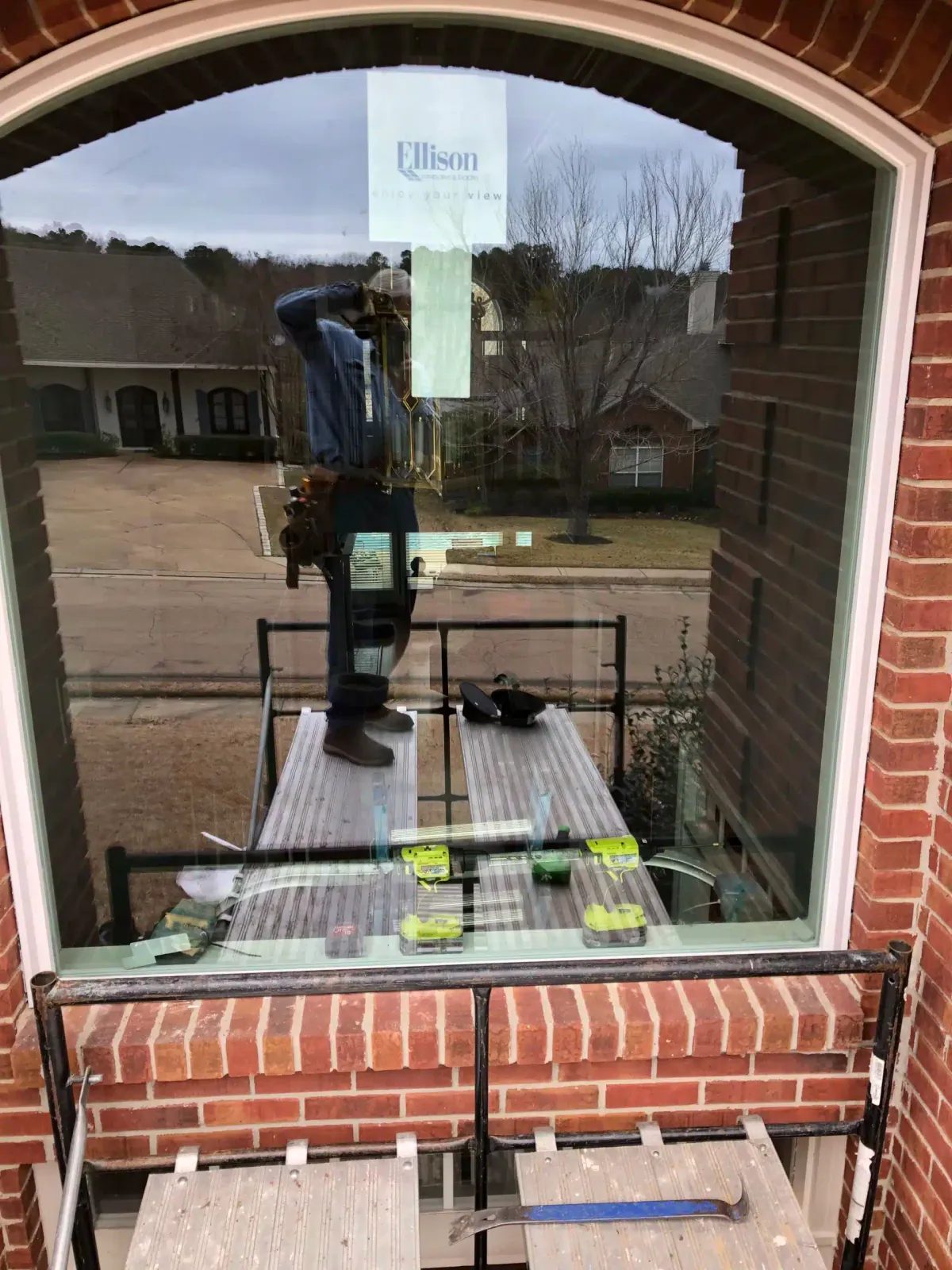 Finished arched window with black frame installed on a two-story brick home