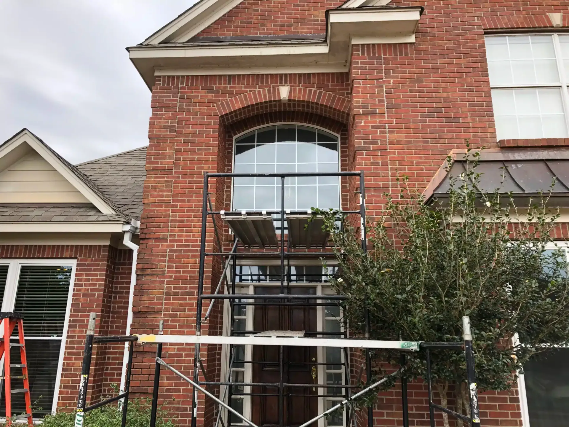 Two-story brick home with an old arched window before replacement