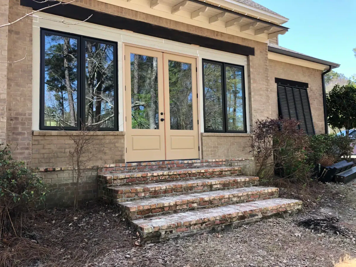 Finished room addition with new French doors, black-framed windows and brick steps