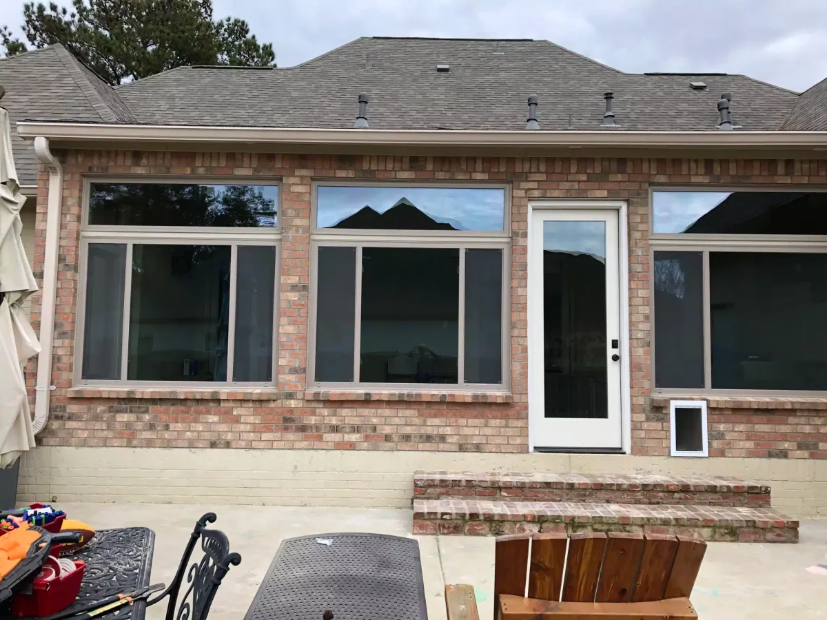 Finished home addition with new picture windows and a white entry door on a brick house