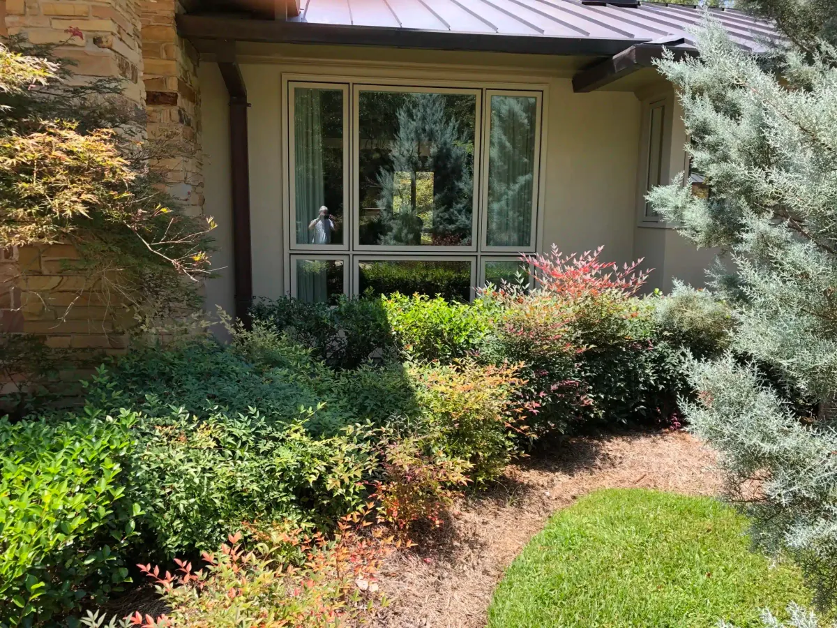 Stone home with the new picture window framed by landscaping