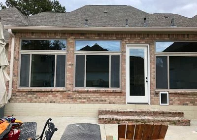 Brick home patio with newly installed picture windows and a white entry door