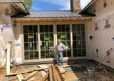 Installer standing beside new French doors on a home addition under construction