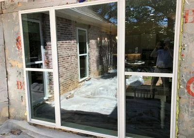 New white window installed in a brick wall with the old opening still exposed