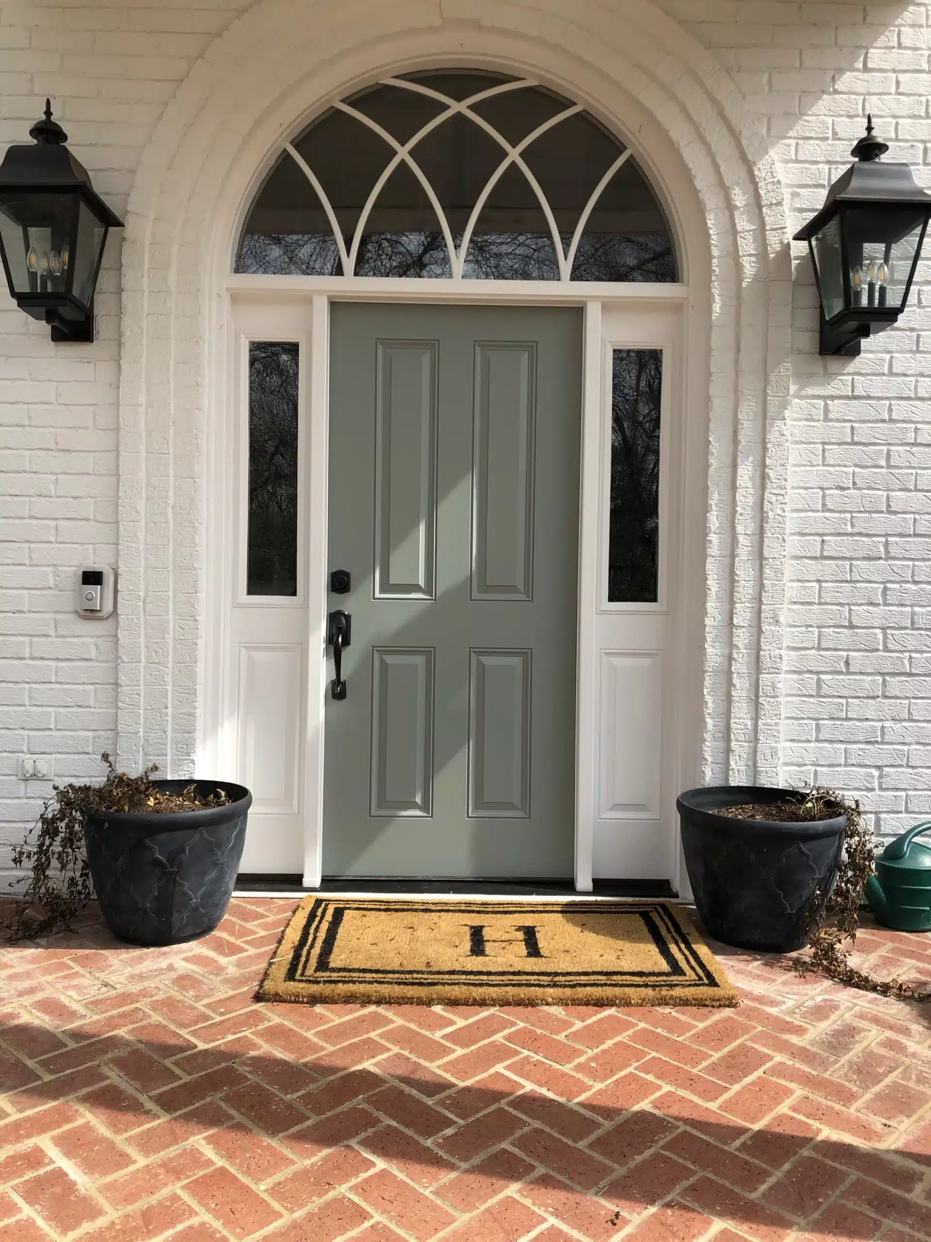 White brick home entry with a new sage-green front door, sidelights and a half-round transom window